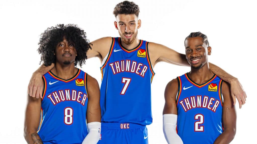 Picture of Oklahoma City Thunder players Jalen Williams, Chet Holmgren, and Shai Gilgeous-Alexander standing in a row. Holmgren has his arms over the shoulders of the others.